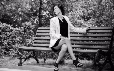 İşten sonra iş yerinde çalışan bir kadın. Şehirde siyah elbiseli ve beyaz ceketli şık bir kadın.