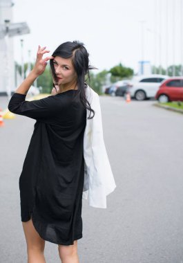 İşten sonra iş yerinde çalışan bir kadın. Şehirde siyah elbiseli ve beyaz ceketli şık bir kadın.