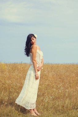 Klasik tonlarda romantik bir portre ve dantelli elbiseli bir kadın sahada duruyor ve doğa ile eğleniyor. Kendini sevme ve çevreyle uyum kavramı.