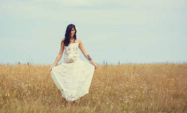 Klasik tonlarda romantik bir portre ve dantelli elbiseli bir kadın sahada duruyor ve doğa ile eğleniyor. Kendini sevme ve çevreyle uyum kavramı.