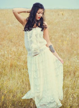 Klasik tonlarda romantik bir portre ve dantelli elbiseli bir kadın sahada duruyor ve doğa ile eğleniyor. Kendini sevme ve çevreyle uyum kavramı.