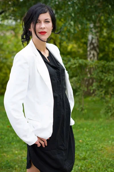 Business woman after work near her office. Stylish dressed woman in black dress and white jacket at the city