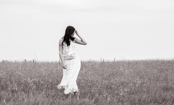 Romantic portrait in vintage tones and texture woman in a lacy clothes standing in the field and enjoying herself and nature. The concept of self love and harmony with the environment