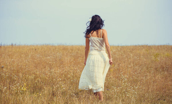 Romantic portrait in vintage tones and texture woman in a lacy clothes standing in the field and enjoying herself and nature. The concept of self love and harmony with the environment