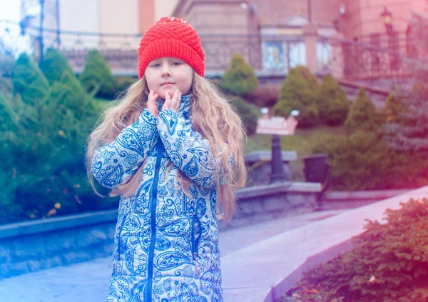 一个穿着蓝色夹克 头戴红帽子的可爱的顽皮小女孩在外面玩耍 享受圣诞假期 冬天街上的儿童游戏 — 图库照片
