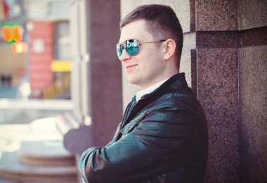 Şehirde güneş gözlüklü genç bir adam portresi. Öğrenci Avrupa 'nın merkezinde yürüyor 