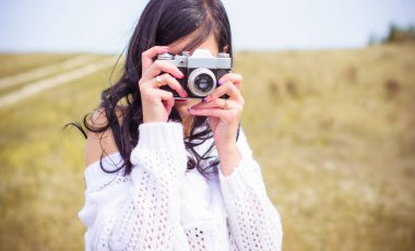 Sahada eski bir fotoğraf makinesi olan genç amatör bir fotoğrafçı mahallenin fotoğraflarını çekiyor. Doğada fotoğraf makinesi olan bir kızın tatilde keyfi yerindedir.