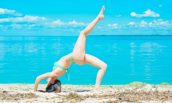 穿着蓝色泳衣在岛上度假的性感瘦小而又性感的黑发女人 她热衷于健身和枕头 在蓝水边和海滩边做瑜伽 放松身心 — 图库照片