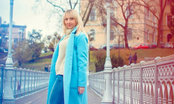 Attractive middle aged woman in blue coat walking in the city. Plus size Fashion woman portrait of trendy lady posing at the city in Europe street fashion