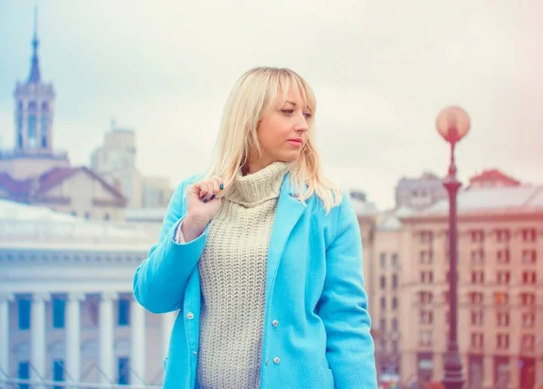 Attractive middle aged woman in blue coat walking in the city. Plus size Fashion woman portrait of trendy lady posing at the city in Europe street fashion