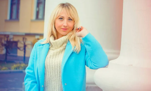 Attractive middle aged woman in blue coat walking in the city. Plus size Fashion woman portrait of trendy lady posing at the city in Europe street fashion