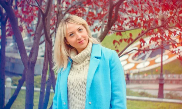 Attractive middle aged woman in blue coat walking in the city. Plus size Fashion woman portrait of trendy lady posing at the city in Europe street fashion