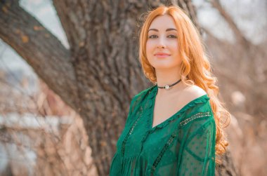 Boho modern tarzı, dantelli yeşil bluz ve etek giyen kızıl saçlı kız. Genç, romantik, kızıl saçlı, sıradan bir kadın, yaşam tarzı portresi.