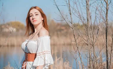 Doğa görünüşü, ortaçağ tarzı kıyafetler, pamuklu, klasik bluz, kemer ve etek giyen kızıl saçlı kadın.