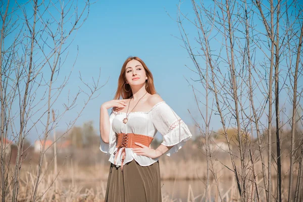 Nature look, Medieval style of clothes, redhead woman in cotton vintage blouse, belt and skirt