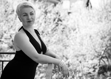 Güzel, orta yaşlı, siyah, eski moda uzun elbiseli, şık aksesuarlı, kolyeli, küpeli ve taşlı yüzüklü bir kadın. Siyah elbiseli kadın. 