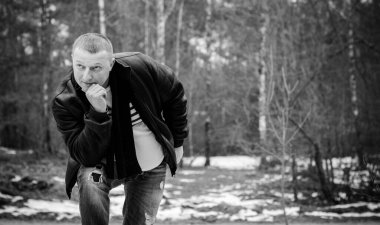 Soğuk bir günde, ormanda, sıcak kıyafetler içinde, orta yaşlı bir adamın portresi. Kış günü ağaçların arka planında siyah ceket giyen şık şık bir adam.