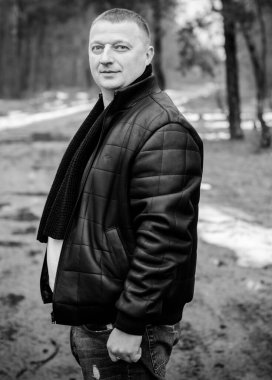 Soğuk bir günde, ormanda, sıcak kıyafetler içinde, orta yaşlı bir adamın portresi. Kış günü ağaçların arka planında siyah ceket giyen şık şık bir adam.