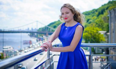 Sarı saçlı kıvırcık kadın artı Avrupalı boy mavi retro elbiseler içinde güneşli sıcak bir günde şehirde yürüyüş.