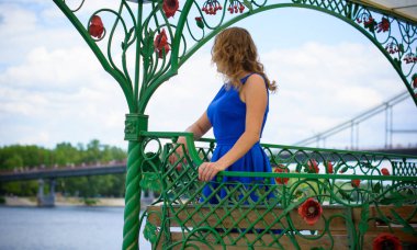 Sarı saçlı kıvırcık kadın artı Avrupalı boy mavi retro elbiseler içinde güneşli sıcak bir günde şehirde yürüyüş.