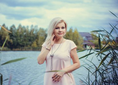 Orta yaşlı, şık, sarışın, güzel bir kadın. Sonbahar bahçesinde deri siyah ceket giymiş, felsefi bir havası var. Güzel aksesuarlı ve doğal bir tarzı olan bir bayan. 