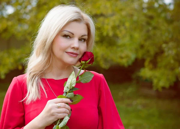 A middle-aged woman in a vintage red dress and accessories for a walk in a small cottage town. The concept of vintage and retro femininity