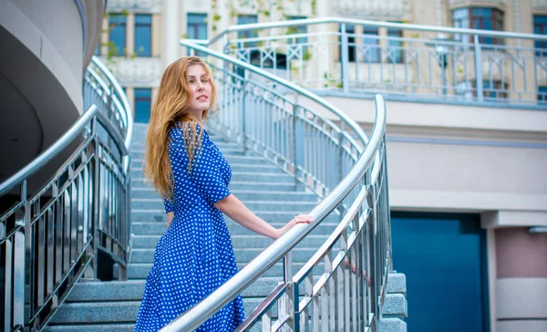 青のレトロなドレスを着た金髪の可愛くて素敵な女の子が休日に街を歩き回り 楽しい一日を楽しんでいます — ストック写真