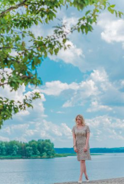 Güzel, sarışın, romantik, iri yarı, deniz kenarında şık, altın elbiseli bir kadın. Moda konsepti, şık kıyafetler.