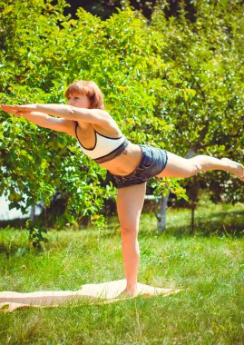 Orta yaşlı bir kadın, güneşli bir günde kendine güveni ve iyi bir ruh hali ile doğada jimnastikle meşgul olur. Sabah egzersizi ve sağlıklı yaşam tarzı.