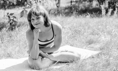 Orta yaşlı bir kadın, güneşli bir günde kendine güveni ve iyi bir ruh hali ile doğada jimnastikle meşgul olur. Sabah egzersizi ve sağlıklı yaşam tarzı.