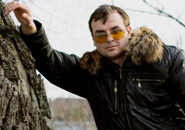 Kürk ceketli gözlüklü bir adam iyi gününde yürüyor ve duyguları var. Doğada sonbahar zamanı dış mekan portresi