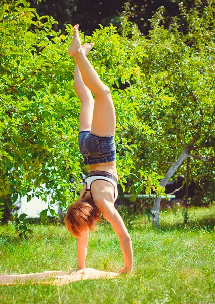 A middle-aged woman is engaged in gymnastics in nature on a bright sunny day with a good mood and faith in herself. Morning exercise and healthy lifestyle