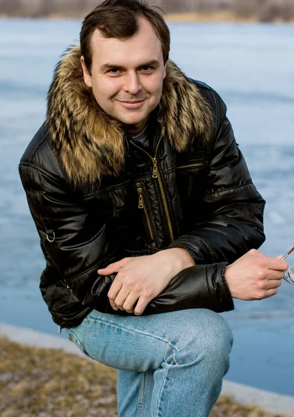 Man with glasses in fur jacket walk at good day and having emotions. Portrait outdoor at nature autumn time