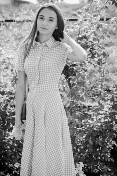 Beautiful young skinny girl walks around the city in a long dress in a cage and enjoys the day