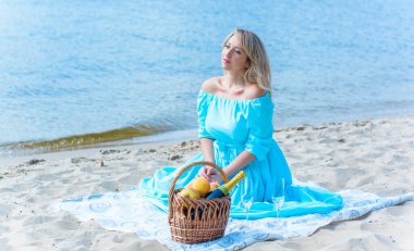 Orta yaşlı bir kadın, artı açık mavi elbiseli, bir şehir rıhtımında tatil gününde dinleniyor. Şehirde kadınlık ve romantizm kavramı