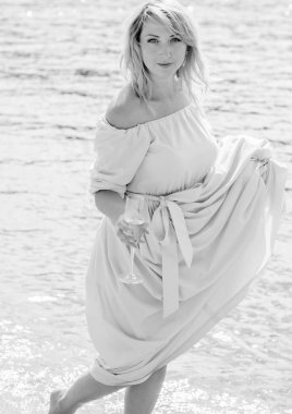 Orta yaşlı bir kadın, artı açık mavi elbiseli, bir şehir rıhtımında tatil gününde dinleniyor. Şehirde kadınlık ve romantizm kavramı 