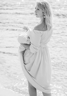 Orta yaşlı bir kadın, artı açık mavi elbiseli, bir şehir rıhtımında tatil gününde dinleniyor. Şehirde kadınlık ve romantizm kavramı 