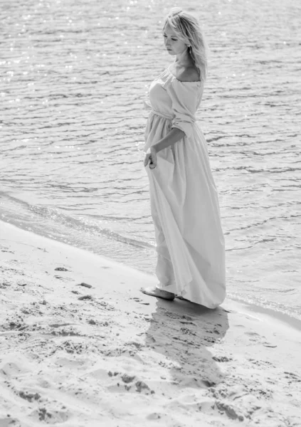 A middle-aged woman, plus in a light blue dress, rests on a city waterfront on a day off. The concept of femininity and romance in the city bustle