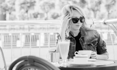 Güzel, şık bir kadın erkek arkadaşını bir randevuda bekliyor. Şehir merkezinde, mimarinin arka planındaki kafede güzel bir bayan.