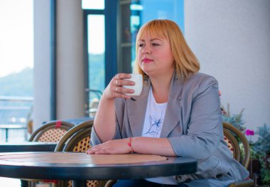 Tombul Amerikalı genç bayan sıcak bir sonbahar gününde terasta oturur ve hayatın tadını çıkarır.