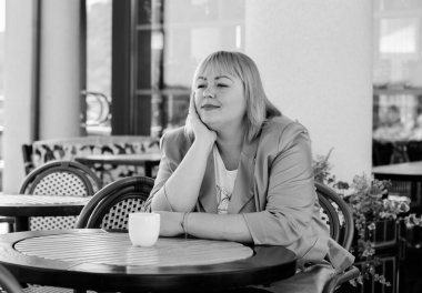 Tombul Amerikalı genç bayan sıcak bir sonbahar gününde terasta oturur ve hayatın tadını çıkarır.