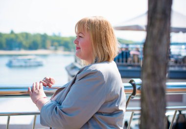 Mutlu kilolu kadın iyi gününde sokaklarda yürüyor. Boyut olarak güneşli bir portre artı bayan. Şehir caddesinde duran güzel şişman kadın.