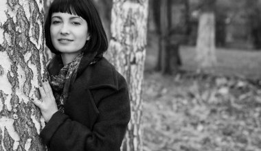 Güzel esmer kadın portresi mavi elbiseli ve ceketli orta yaşlı, renkli eşarplı, parktaki aksesuarlar soğuk hava koşullarında ormanda.