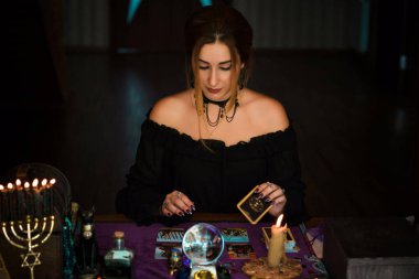  Tarot kartlarındaki kadın falcı, kehanet kavramı, sihirli ritüeller ve masanın üzerindeki cadı unsurları.
