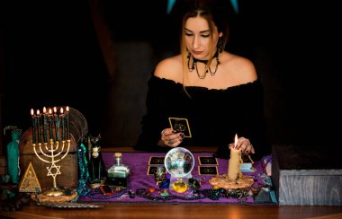  Tarot kartlarındaki kadın falcı, kehanet kavramı, sihirli ritüeller ve masanın üzerindeki cadı unsurları.