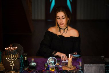  Tarot kartlarındaki kadın falcı, kehanet kavramı, sihirli ritüeller ve masanın üzerindeki cadı unsurları.