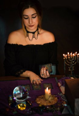  Tarot kartlarındaki kadın falcı, kehanet kavramı, sihirli ritüeller ve masanın üzerindeki cadı unsurları.