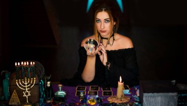Kristal kürenin üstündeki kadın falcı, kehanetler, sihirli ritüeller ve cadılık kavramı.
