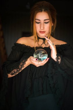 Kristal kürenin üstündeki kadın falcı, kehanetler, sihirli ritüeller ve cadılık kavramı.