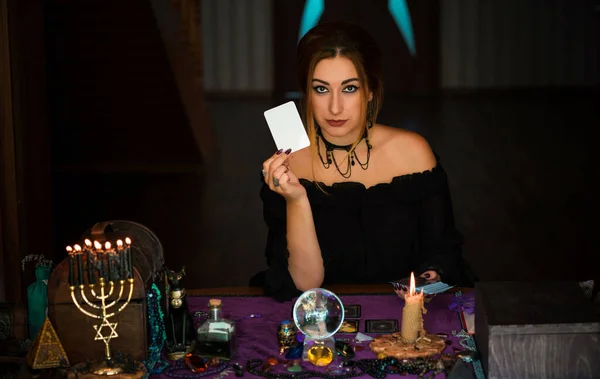 Beyaz tarot kartı tutan kadın kehanetler, sihirli ritüeller ve cadılık kavramı.